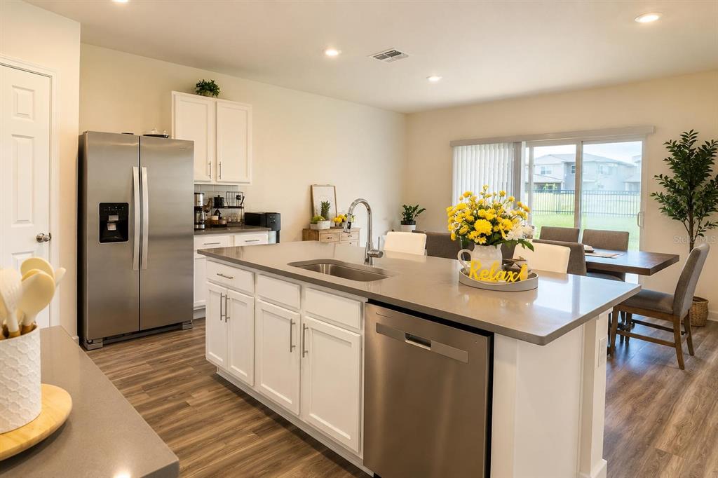 A modern kitchen features white cabinets, stainless steel appliances, and a large central island — 4002 MALAWI TRAIL, ST CLOUD, FL
