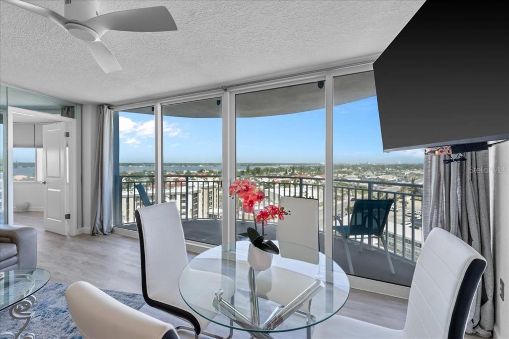 A dining area with a glass table and white chairs overlooks a balcony and water — 2625 S ATLANTIC AVENUE UNIT 11NW, DAYTONA BEACH, FL