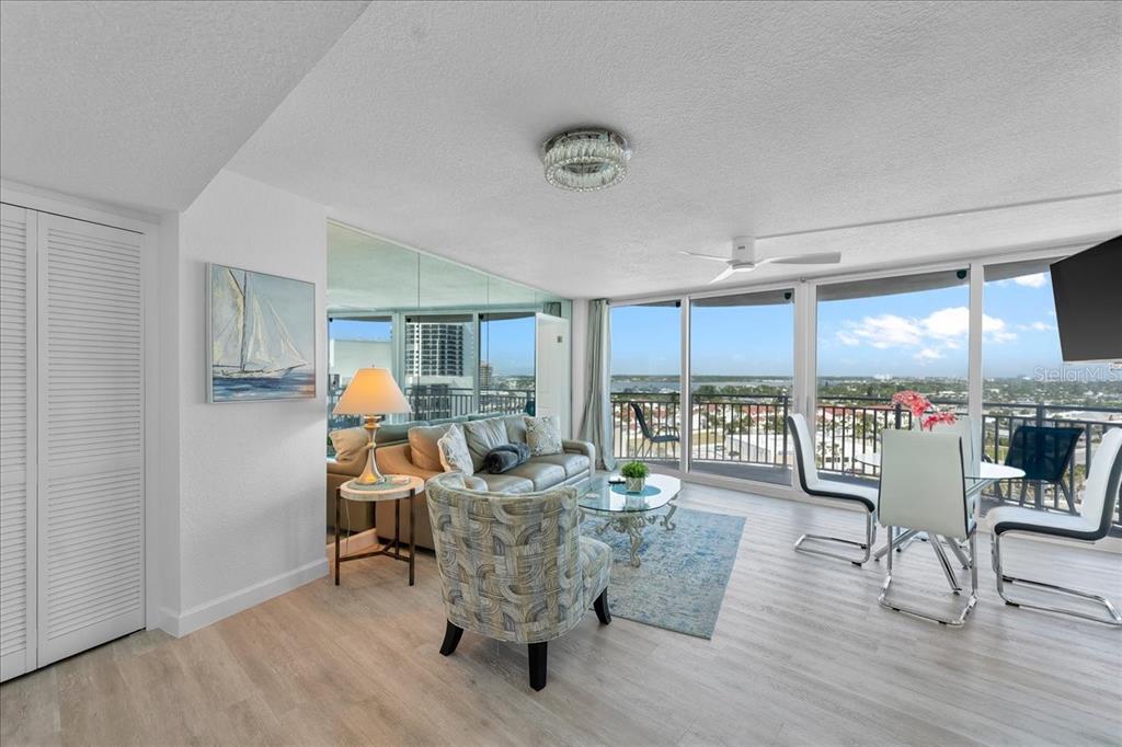 A living and dining area features light wood floors, a mirrored wall, and balcony views — 2625 S ATLANTIC AVENUE UNIT 11NW, DAYTONA BEACH, FL