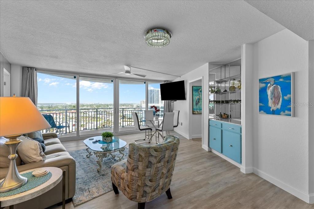 A living room features a sofa, patterned armchair, glass coffee table, and a blue wet bar — 2625 S ATLANTIC AVENUE UNIT 11NW, DAYTONA BEACH, FL
