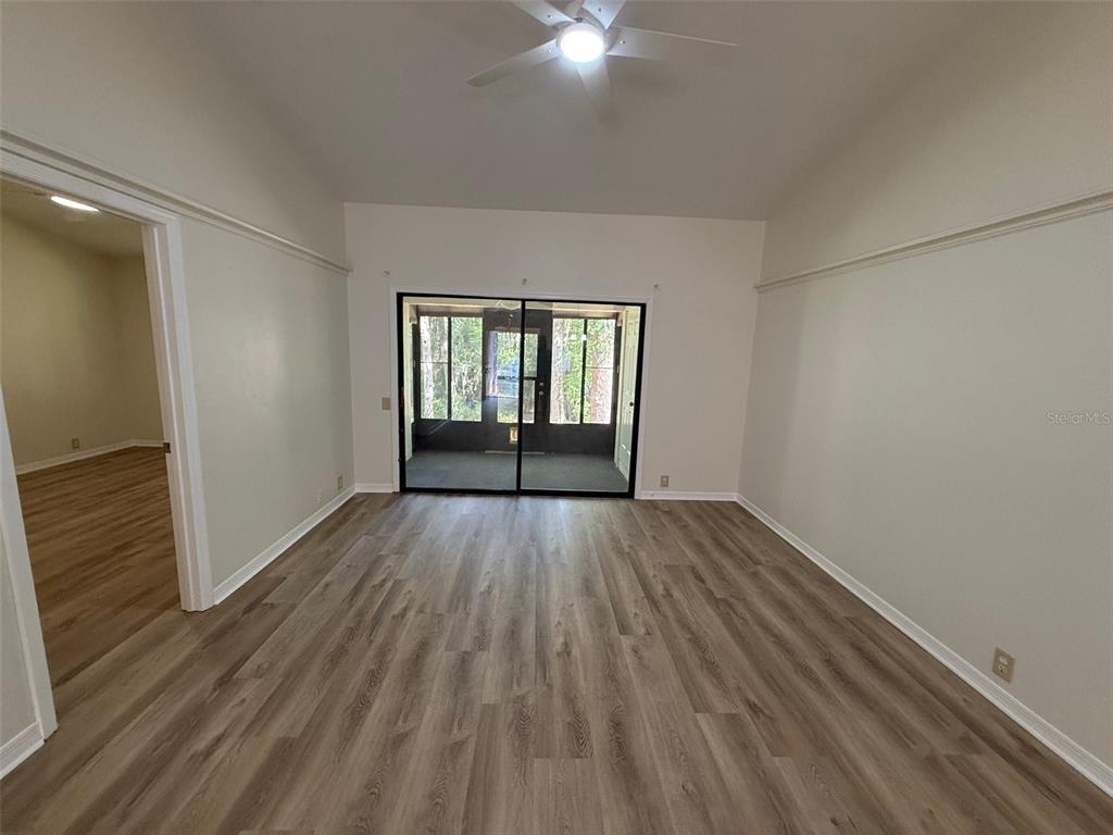 A room with light wood-look flooring, white walls, a ceiling fan, and sliding glass doors — 4052 NW 23RD CIRCLE, GAINESVILLE, FL