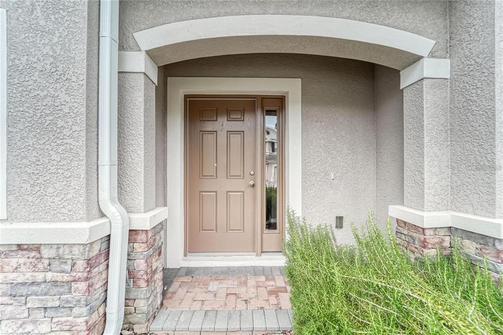 A front entryway features a tan door with a sidelight, stone accents, and a brick porch — 3903 SILVERLAKE WAY, WESLEY CHAPEL, FL