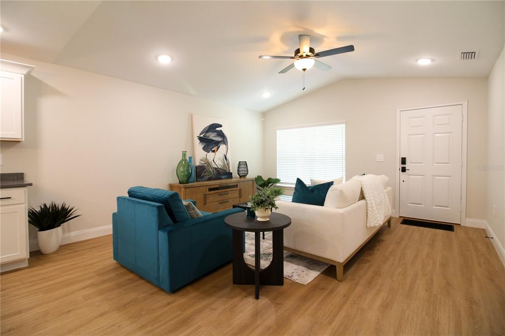 A living room features light wood flooring, a white sofa, a teal armchair, and a ceiling fan — 1242 DOROTHY STREET, LAKELAND, FL