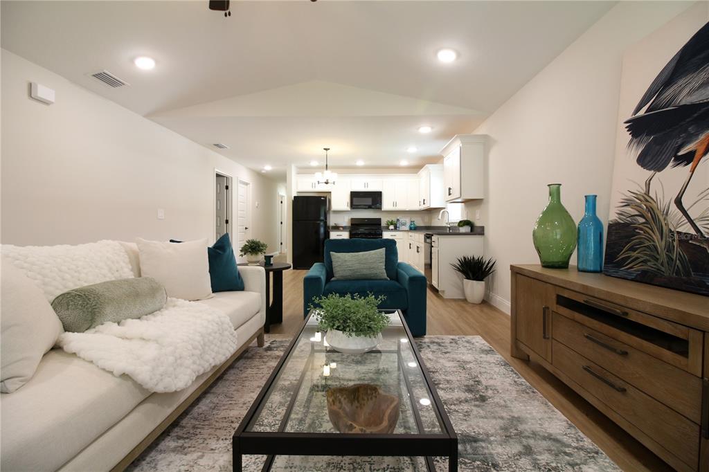 A living room with a white sofa and blue armchair opens into a white kitchen — 1242 DOROTHY STREET, LAKELAND, FL