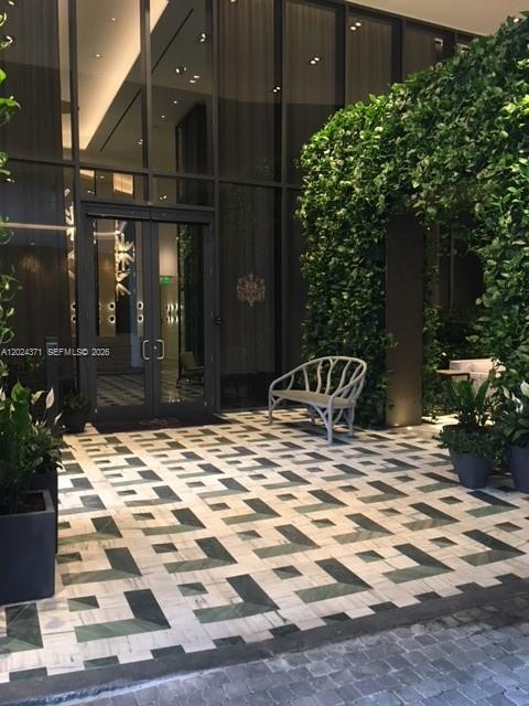 A modern building entrance features a patterned stone floor, glass doors, and a decorative bench — 801 S Miami Ave # 2808, Miami FL 33130, MIAMI, FL
