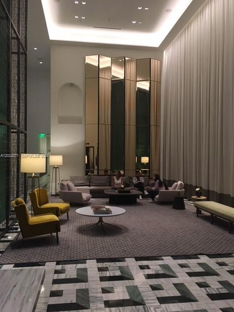 A modern hotel lobby features tall ceilings, floor-to-ceiling mirrors, and a large seating area — 801 S Miami Ave # 2808, Miami FL 33130, MIAMI, FL