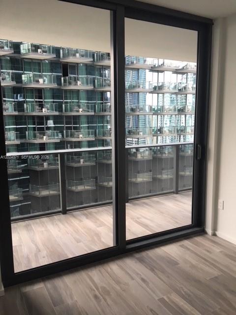A room with light wood-look flooring and a large sliding glass door leading to a balcony — 801 S Miami Ave # 2808, Miami FL 33130, MIAMI, FL