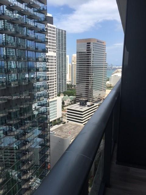 A high-angle view from a balcony overlooking city skyscrapers and a distant coastline — 801 S Miami Ave # 2808, Miami FL 33130, MIAMI, FL