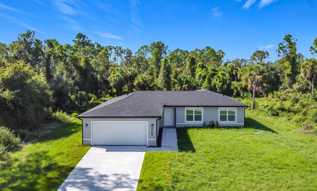 A single-story house with a white exterior, dark trim, and a two-car garage — 3716 5TH STREET W, LEHIGH ACRES, FL