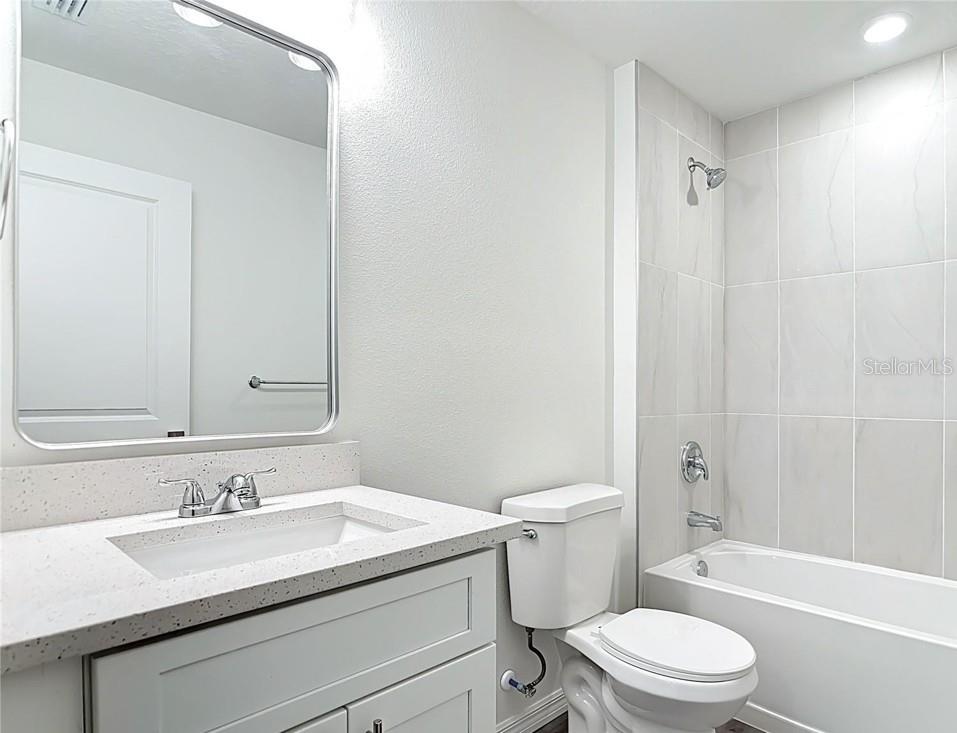 A single-story house with a white garage, a concrete driveway, and a large grassy yard — 3716 5TH STREET W, LEHIGH ACRES, FL