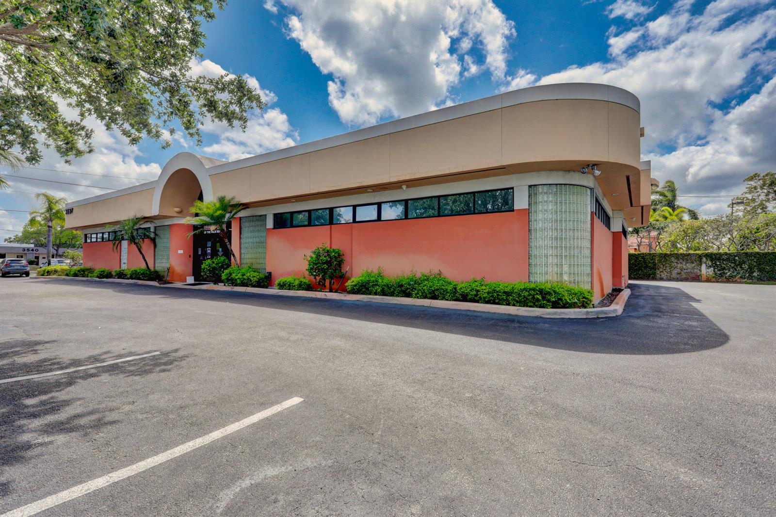 A low-rise commercial building with a curved corner, glass block accents, and a parking lot — 3537 Forest Hill Boulevard, West Palm Beach FL 33406, WEST PALM BEACH, FL