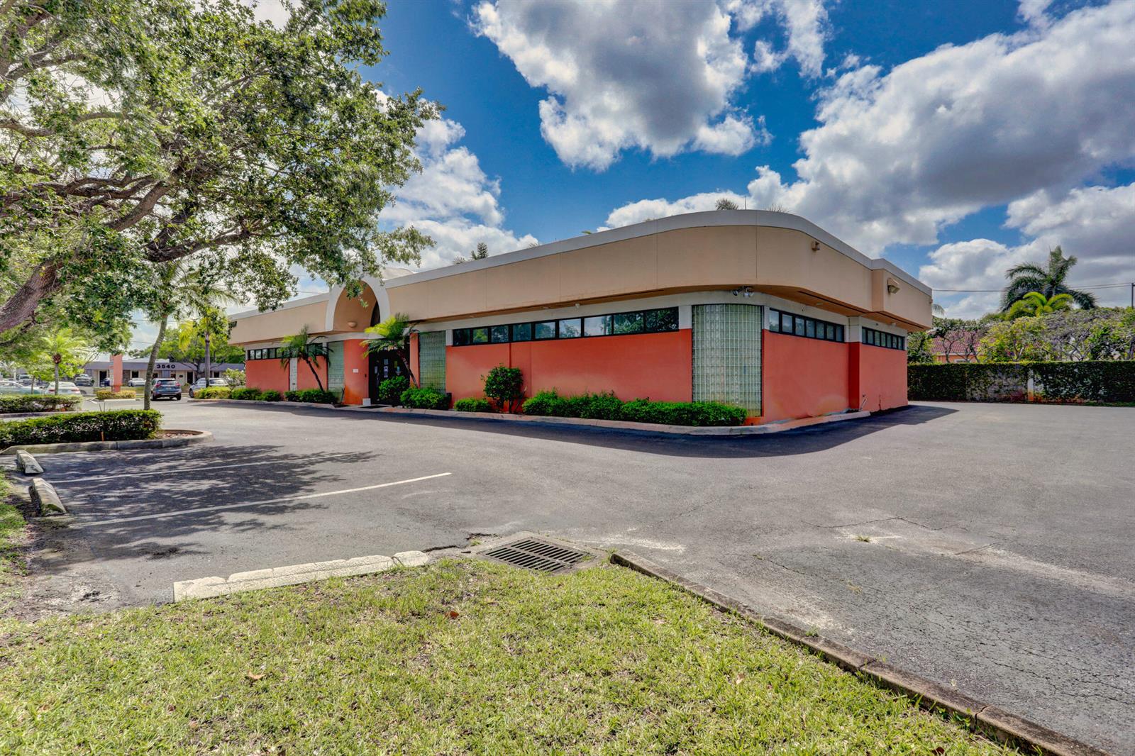 A single-story commercial building with orange walls, glass block accents, and a large parking lot — 3537 Forest Hill Boulevard, West Palm Beach FL 33406, WEST PALM BEACH, FL