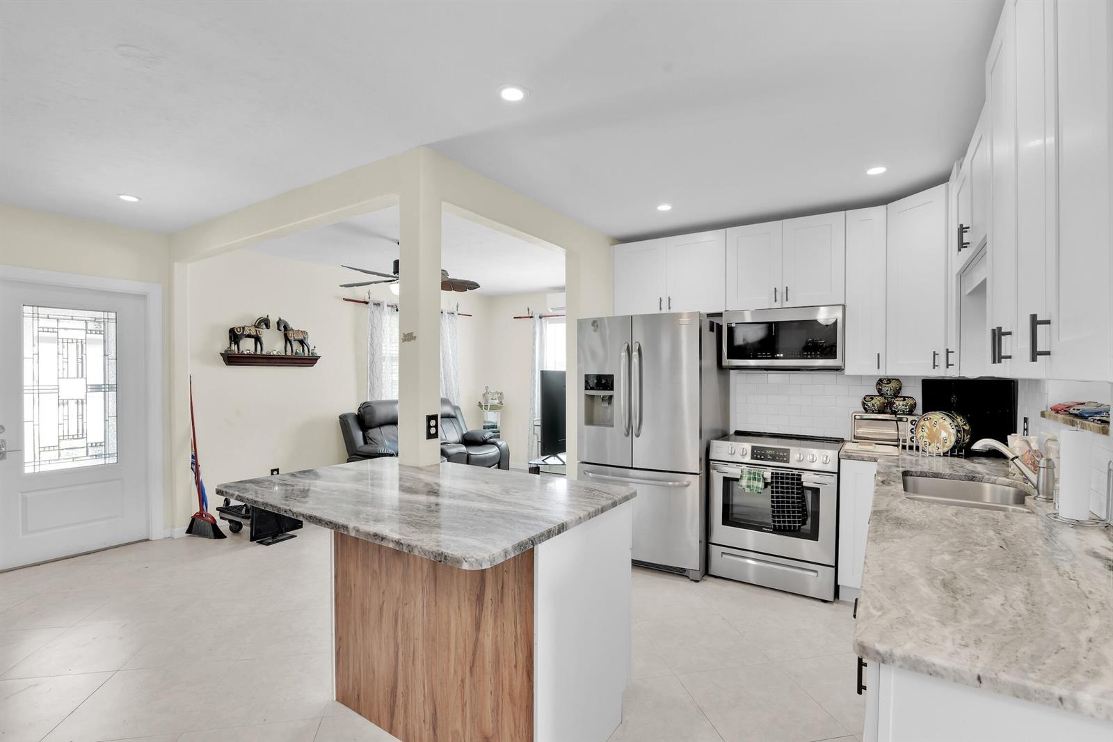 A kitchen with white cabinets, stainless steel appliances, and a marble-topped island — 5221 NE 16th Avenue, Pompano Beach FL 33064, POMPANO BEACH, FL