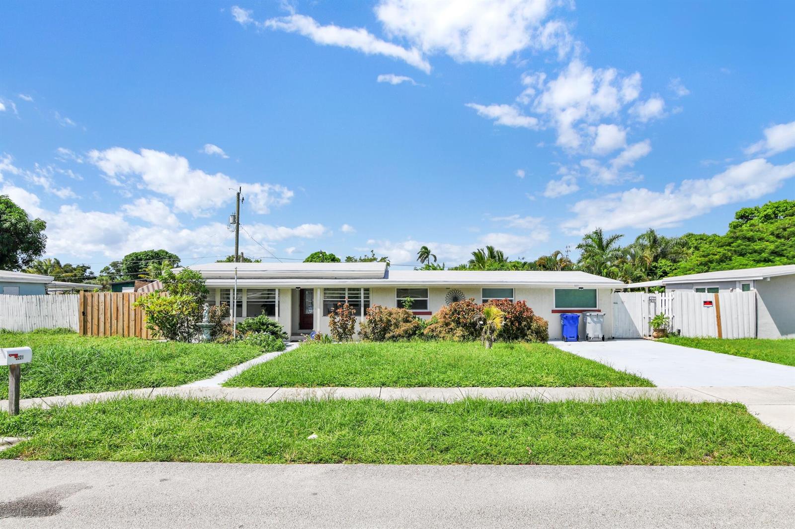 A single-story house with a white exterior, a front lawn, and a concrete driveway — 5221 NE 16th Avenue, Pompano Beach FL 33064, POMPANO BEACH, FL
