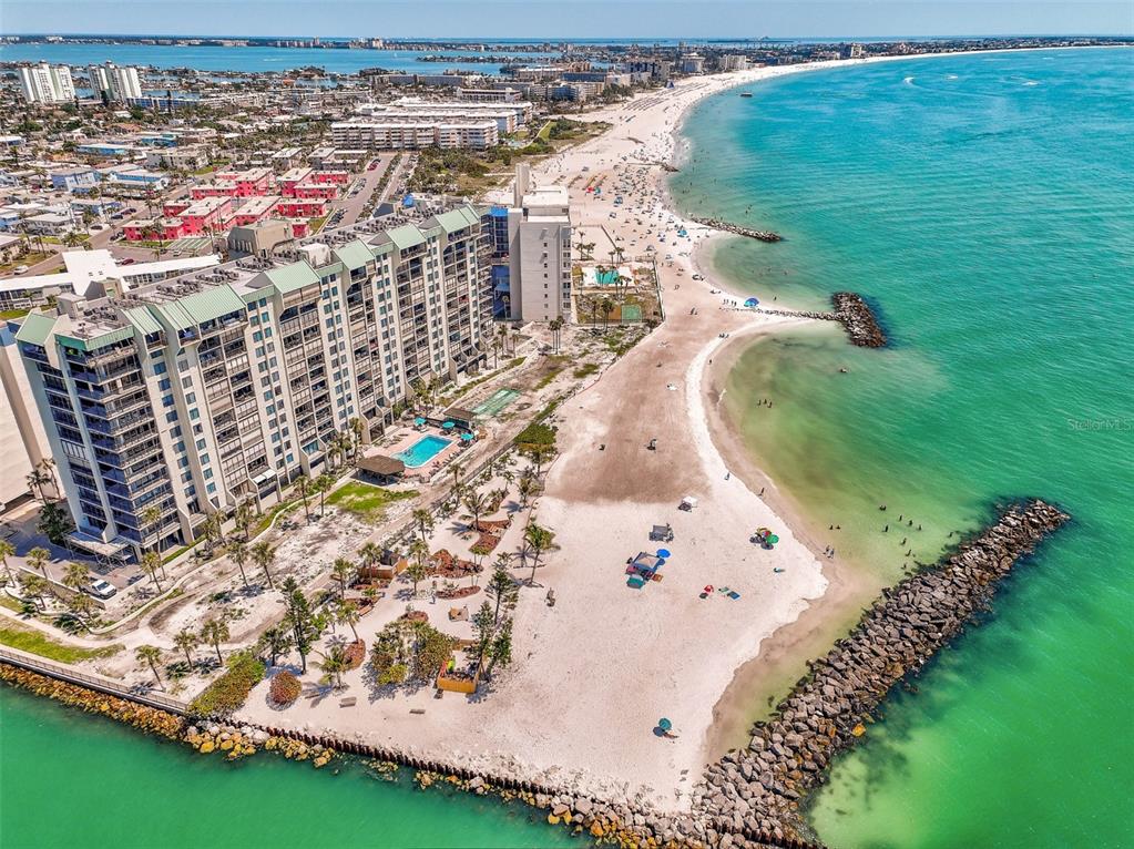 An aerial view of a beachfront condominium building next to a sandy beach and ocean — 7100 SUNSET WAY UNIT 310, ST PETE BEACH, FL