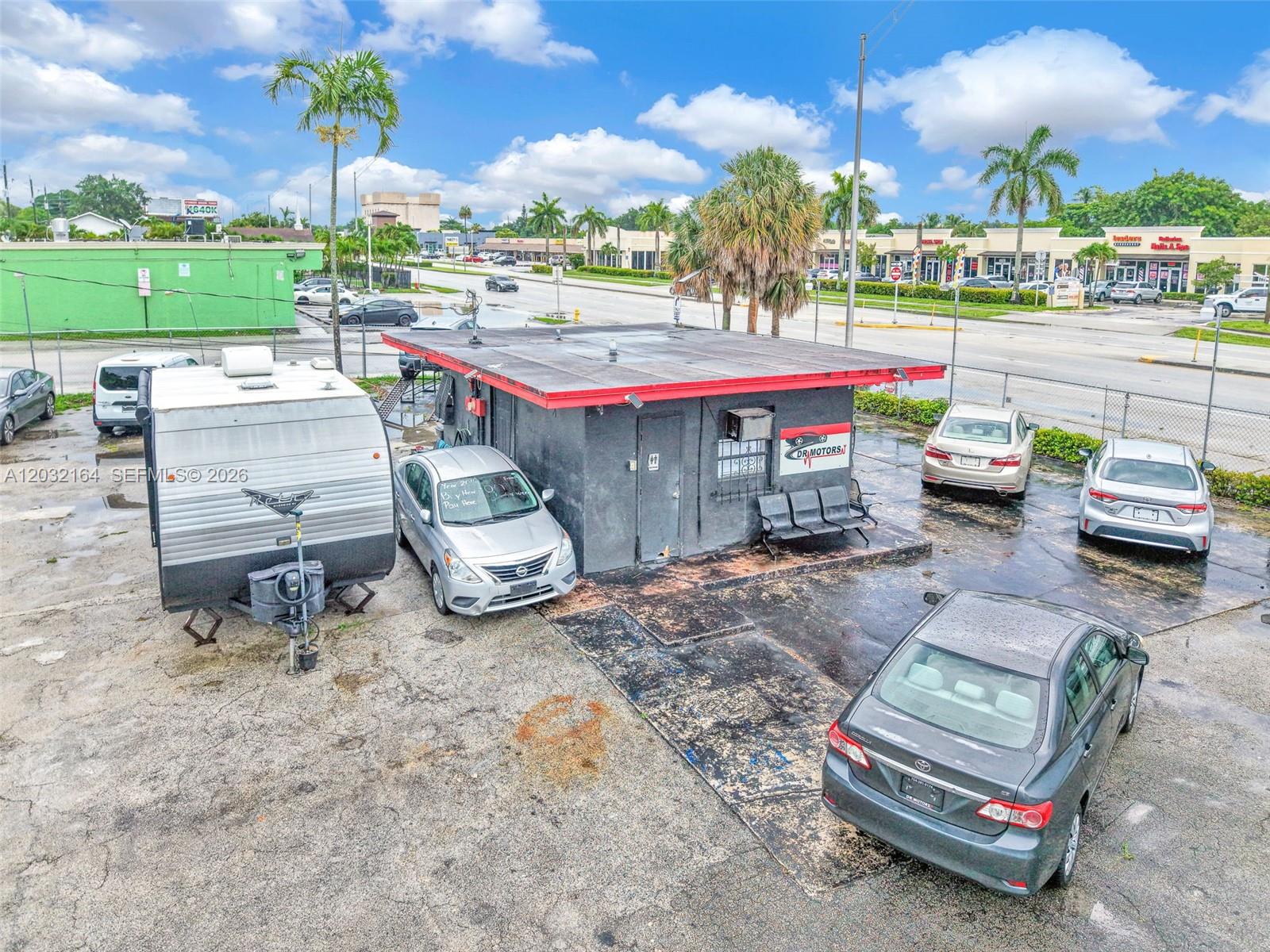An aerial view shows a small commercial building with a red-trimmed roof and surrounding parking — 4601 W Hallandale Beach Blvd, Hollywood FL 33023, HOLLYWOOD, FL