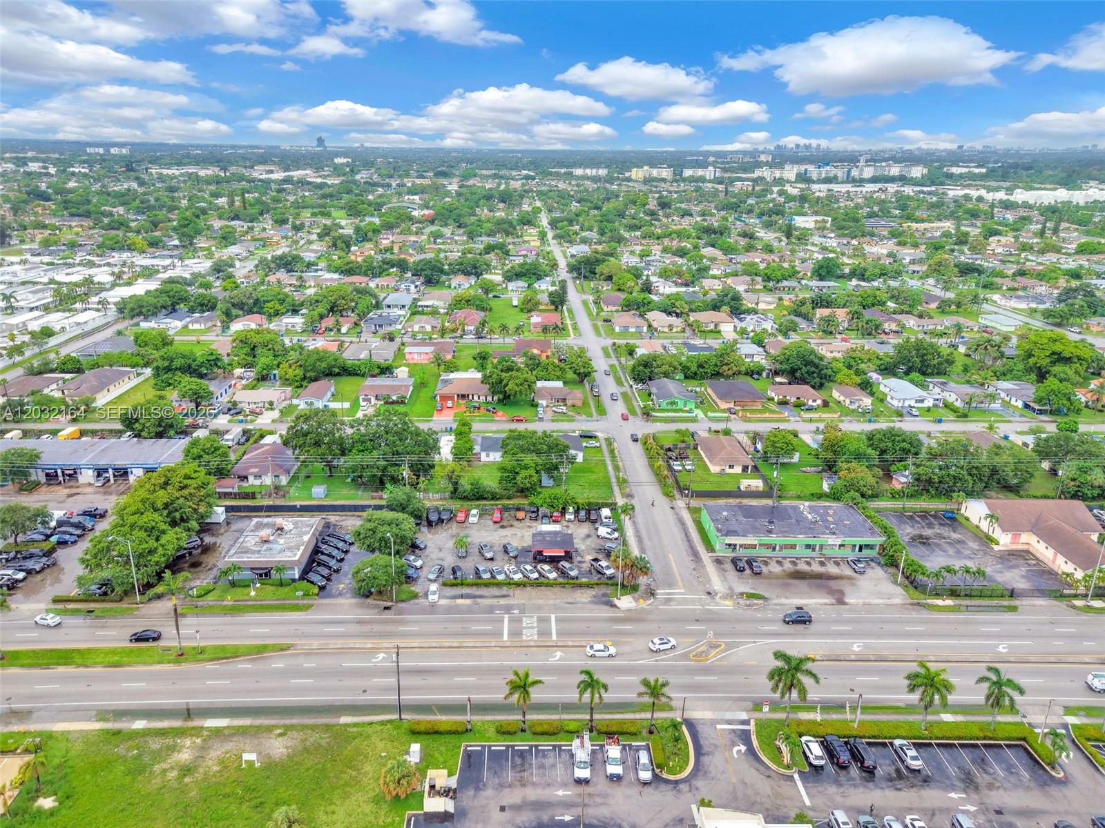 An aerial view shows a suburban neighborhood with houses, commercial buildings, and a multi-lane road — 4601 W Hallandale Beach Blvd, Hollywood FL 33023, HOLLYWOOD, FL