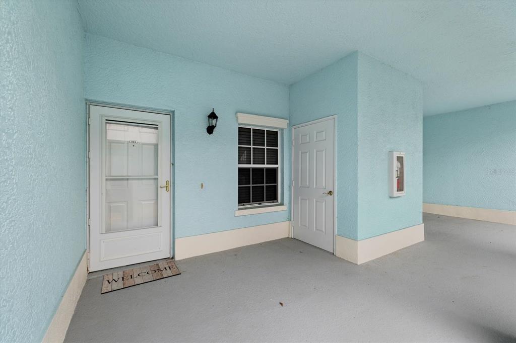 A light blue exterior entryway features a white front door, a window, and a utility door — 5738 SABAL TRACE DRIVE UNIT 1B5738, NORTH PORT, FL