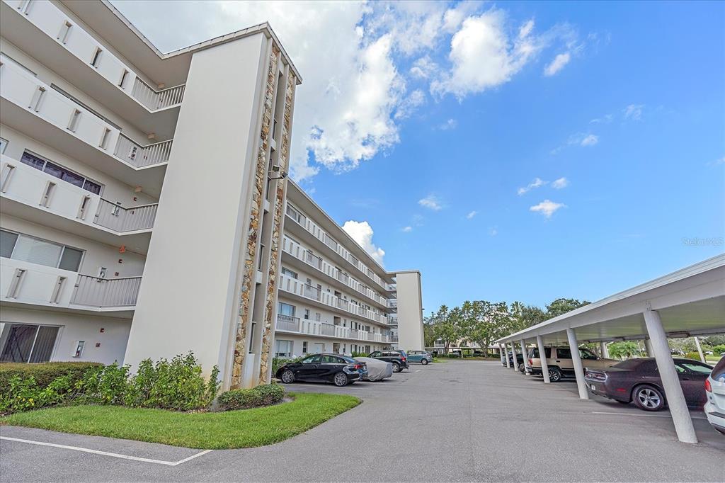 A multi-story apartment building with balconies and a covered parking area in the foreground — 4210 IRONWOOD CIRCLE UNIT 103J, BRADENTON, FL