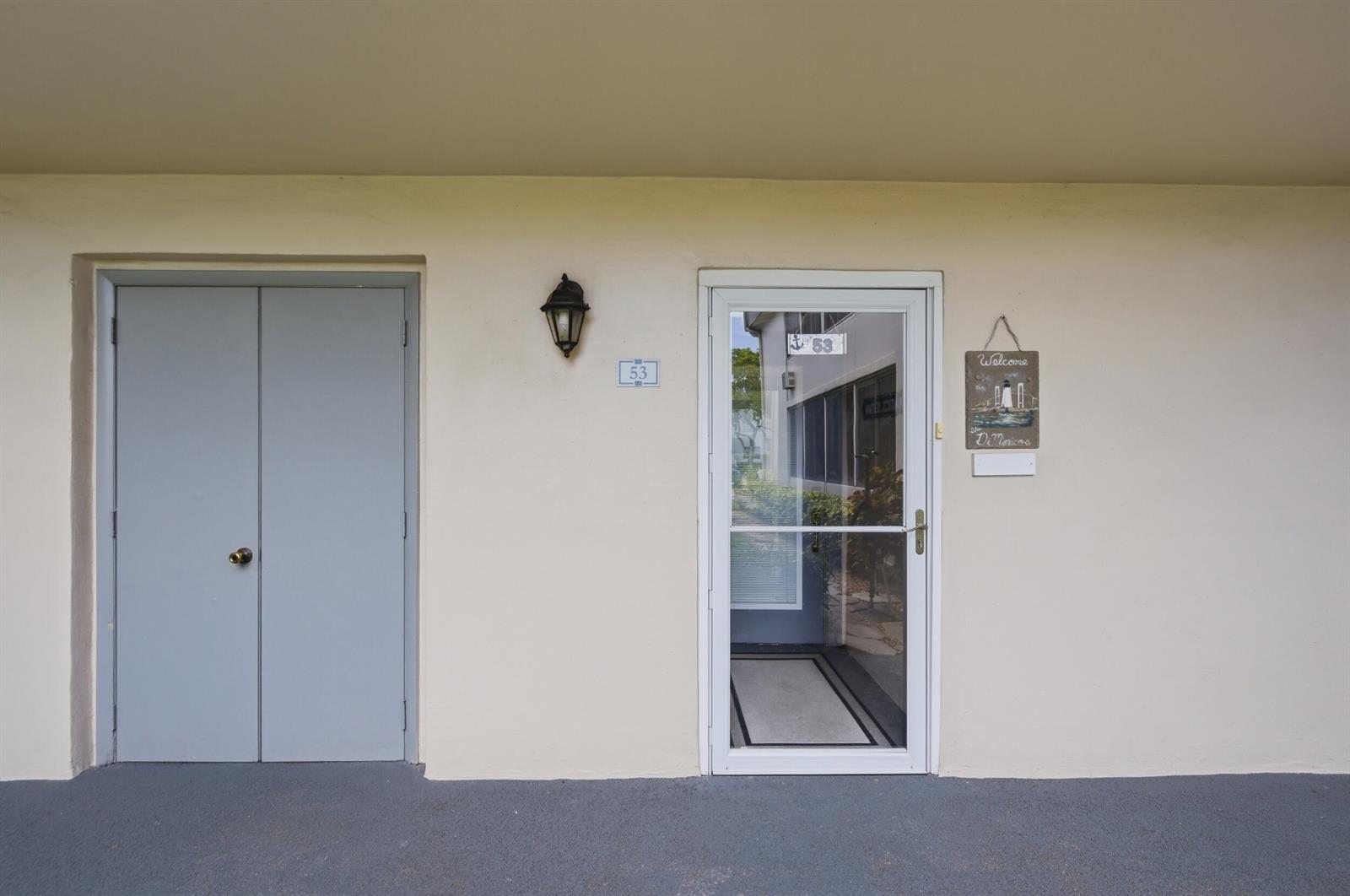 An exterior view of a building entrance with a grey door and a glass storm door — 53 Piedmont B, Delray Beach FL 33484, DELRAY BEACH, FL