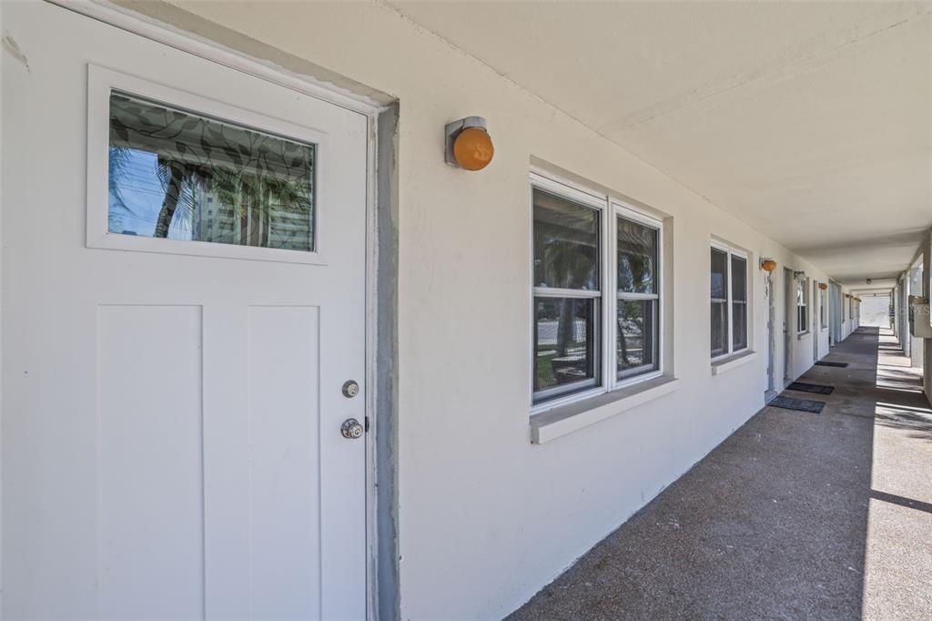 An exterior view of a white building with a walkway, doors, and windows — 4565 DUHME ROAD UNIT 102, ST PETERSBURG, FL