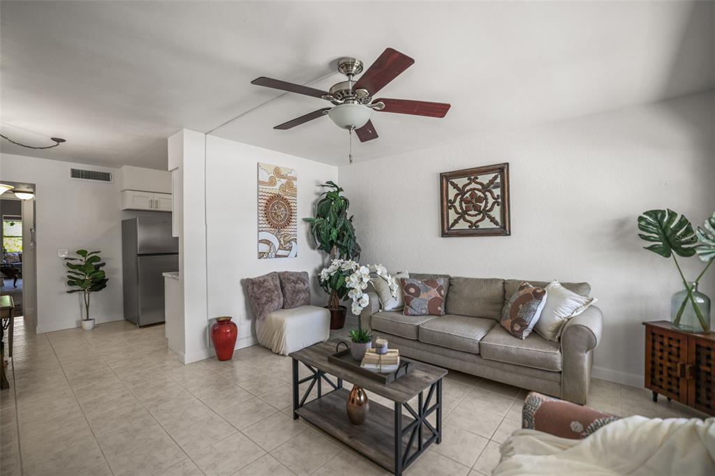 A living room features a beige sofa, a wooden coffee table, and a ceiling fan — 4565 DUHME ROAD UNIT 102, ST PETERSBURG, FL