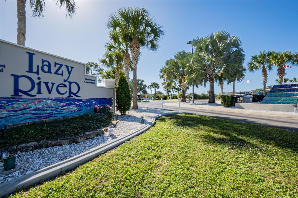 A sign for Lazy River Waterfront Community stands beside a road lined with palm trees — 107 TORTOLA WAY, NORTH PORT, FL