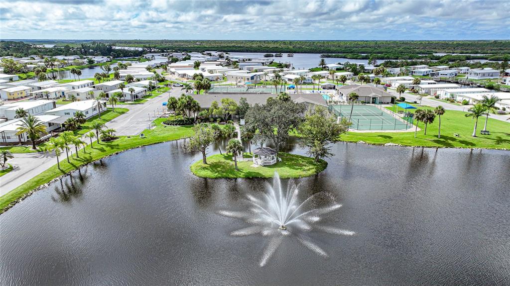 An aerial view shows a pond with a fountain and gazebo surrounded by residential homes — 107 TORTOLA WAY, NORTH PORT, FL