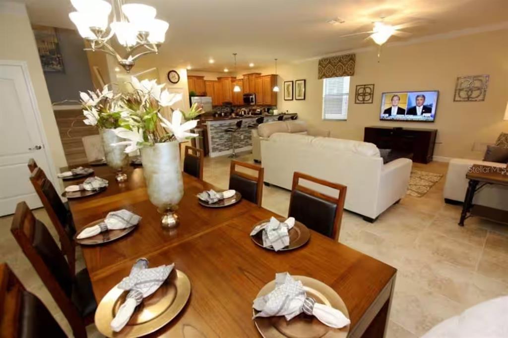 A dining area with a wooden table leads into an open-concept kitchen and living room — 1524 MOON VALLEY DRIVE, DAVENPORT, FL