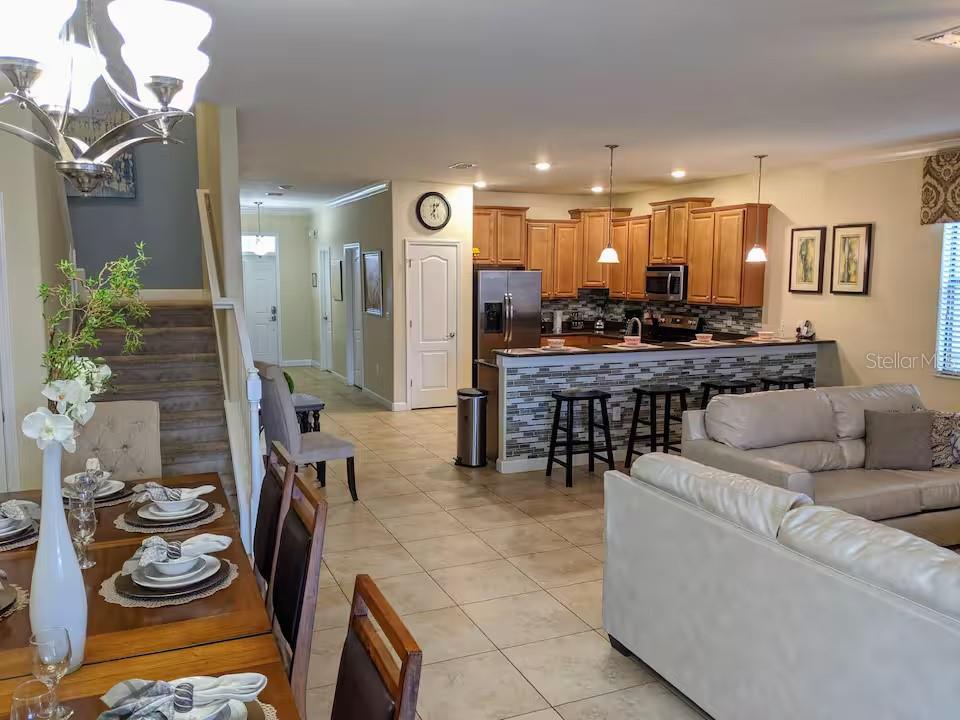 An open-concept kitchen with wood cabinets and a breakfast bar overlooks a living and dining area — 1524 MOON VALLEY DRIVE, DAVENPORT, FL