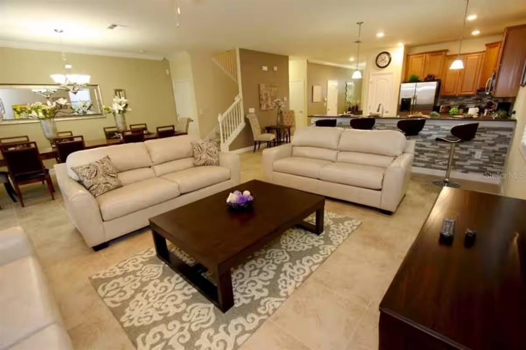 An open-concept living room features two white sofas, a dark coffee table, and a kitchen — 1524 MOON VALLEY DRIVE, DAVENPORT, FL