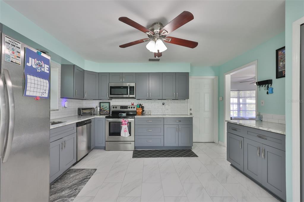 A kitchen with gray cabinets, white subway tile backsplash, stainless steel appliances, and tile flooring — 2335 SURREY LANE, CLEARWATER, FL