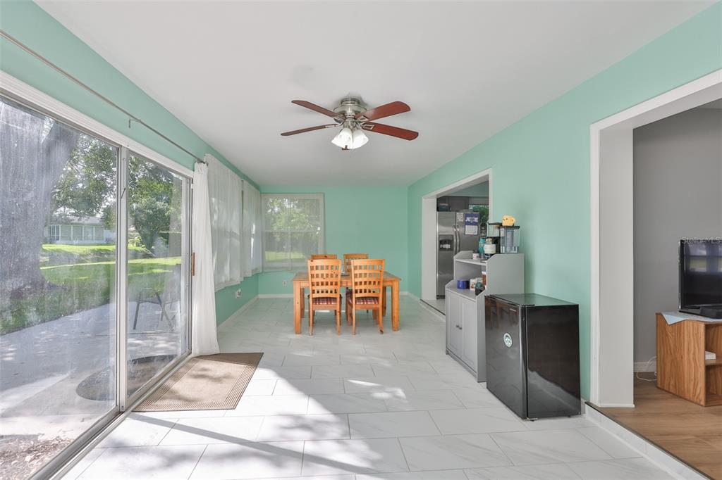 A sunroom with light green walls, white tile flooring, a dining set, and sliding glass doors — 2335 SURREY LANE, CLEARWATER, FL