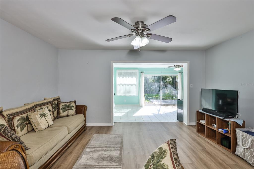 A living room with light gray walls, wood-look flooring, a ceiling fan, and a sofa — 2335 SURREY LANE, CLEARWATER, FL