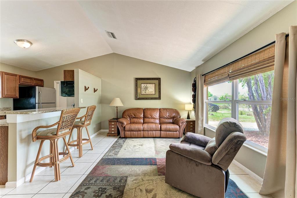 A living room features a brown leather sofa, a recliner, and a kitchen breakfast bar — 6310 CUTLER TERRACE, PORT CHARLOTTE, FL