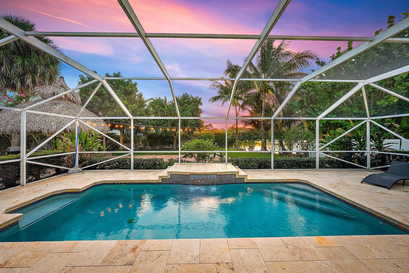 A screened-in swimming pool with a stone deck, water feature, and tropical backyard landscaping — 15129 Harriet Avenue, Jupiter FL 33458, JUPITER, FL