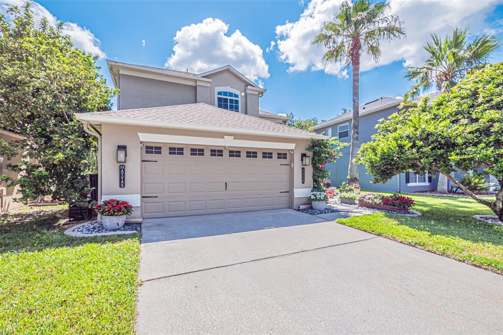 A two-story house features a tan exterior, a two-car garage, and a palm tree — 4315 NORTHERN DANCER WAY, ORLANDO, FL