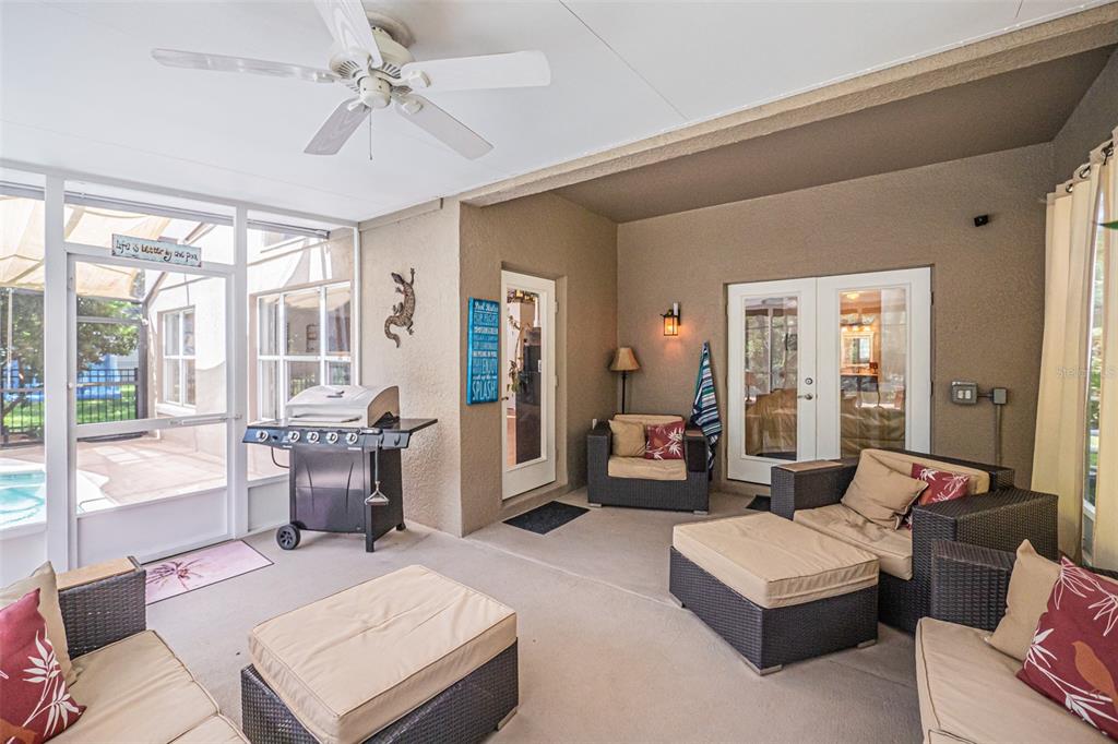 A screened-in patio features wicker furniture, a grill, and a ceiling fan overlooking a pool — 4315 NORTHERN DANCER WAY, ORLANDO, FL