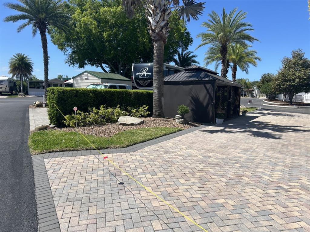 A paved driveway leads to a gazebo and a parked RV near a hedge — 2505 PINE STREET, CLERMONT, FL