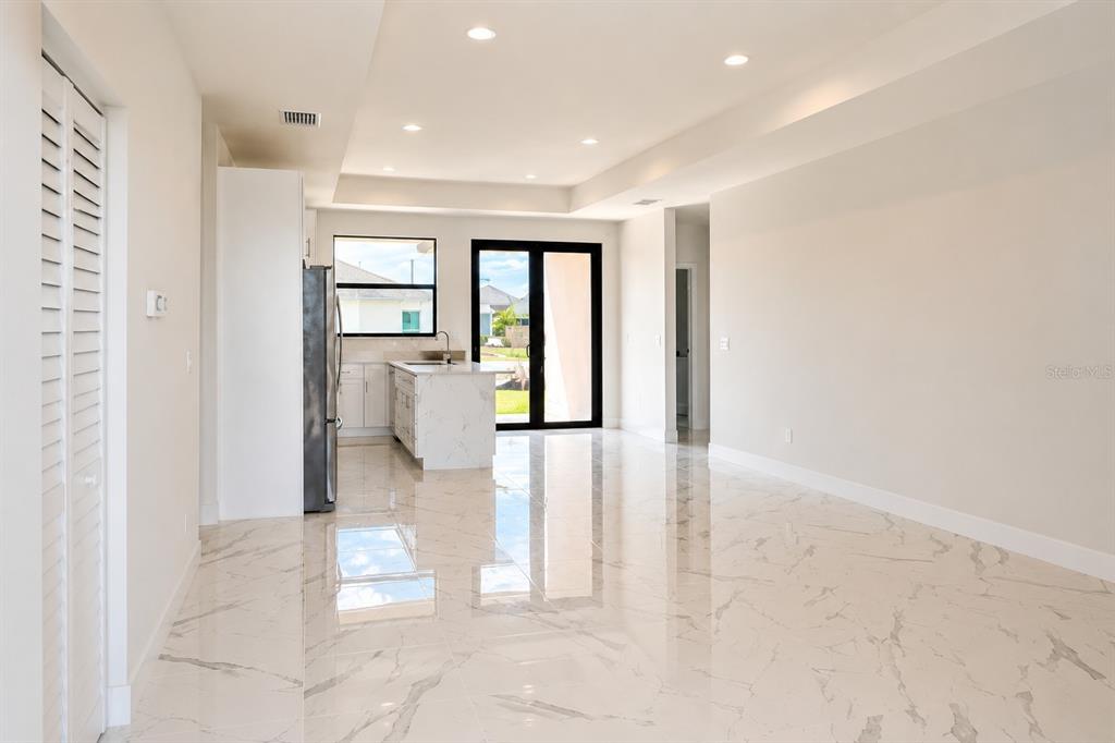 An open-concept kitchen and living area features white marble-look tile flooring and recessed lighting — 1107 NW 9TH AVENUE, CAPE CORAL, FL