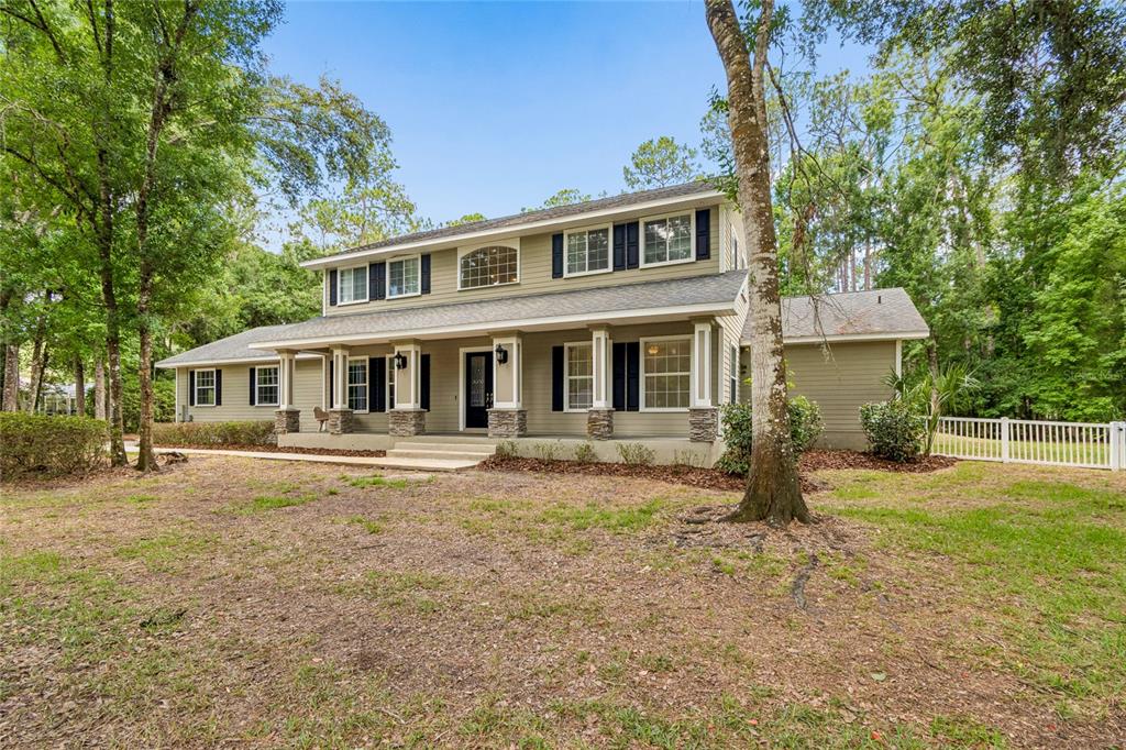 A two-story house with light green siding, a covered front porch, and dark shutters — 27708 SANTA ANITA BOULEVARD, WESLEY CHAPEL, FL