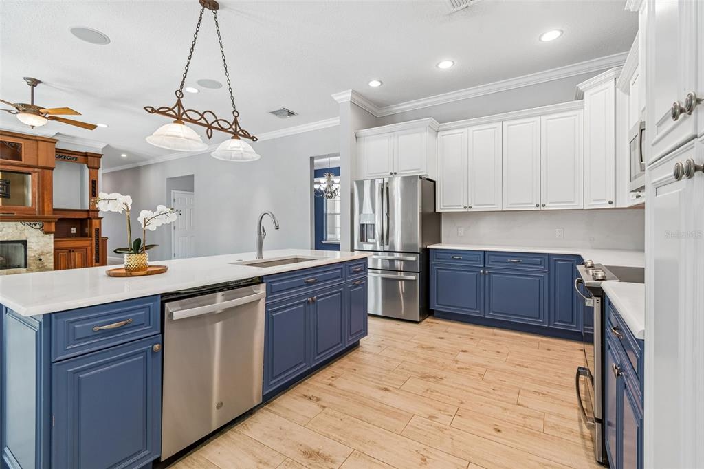 A kitchen features blue lower cabinets, white upper cabinets, stainless steel appliances, and a white island — 27708 SANTA ANITA BOULEVARD, WESLEY CHAPEL, FL