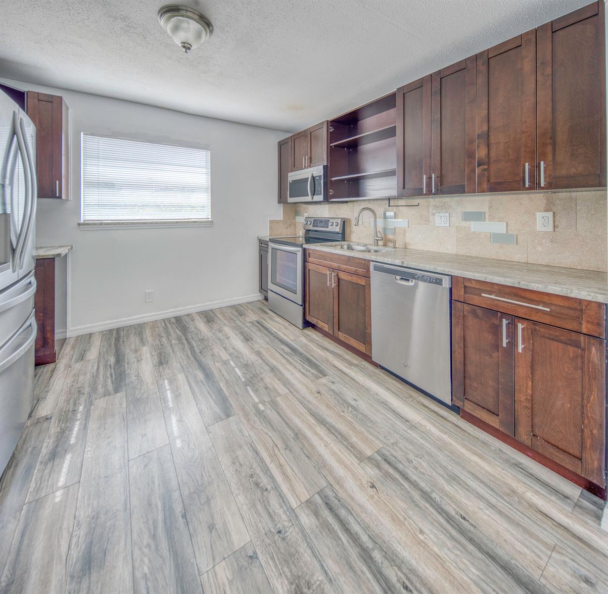 A kitchen features dark wood cabinets, stainless steel appliances, and wood-look flooring — 216 S Ocean Breeze, Lake Worth FL 33460, LAKE WORTH, FL