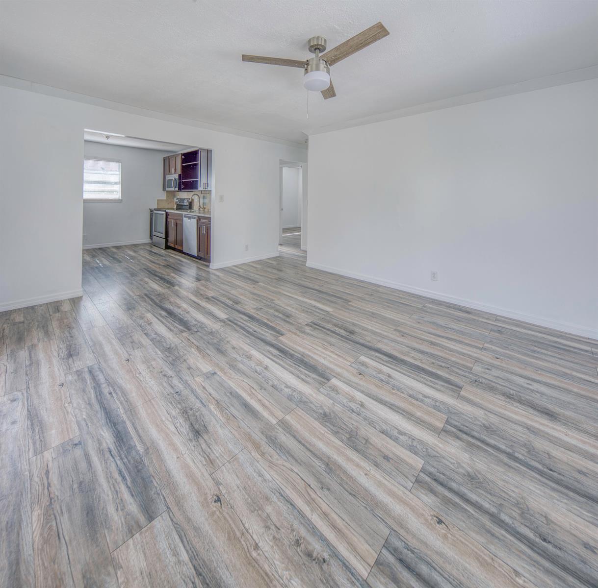 An open-concept living area features light-colored wood-look flooring, white walls, and a ceiling fan — 216 S Ocean Breeze, Lake Worth FL 33460, LAKE WORTH, FL