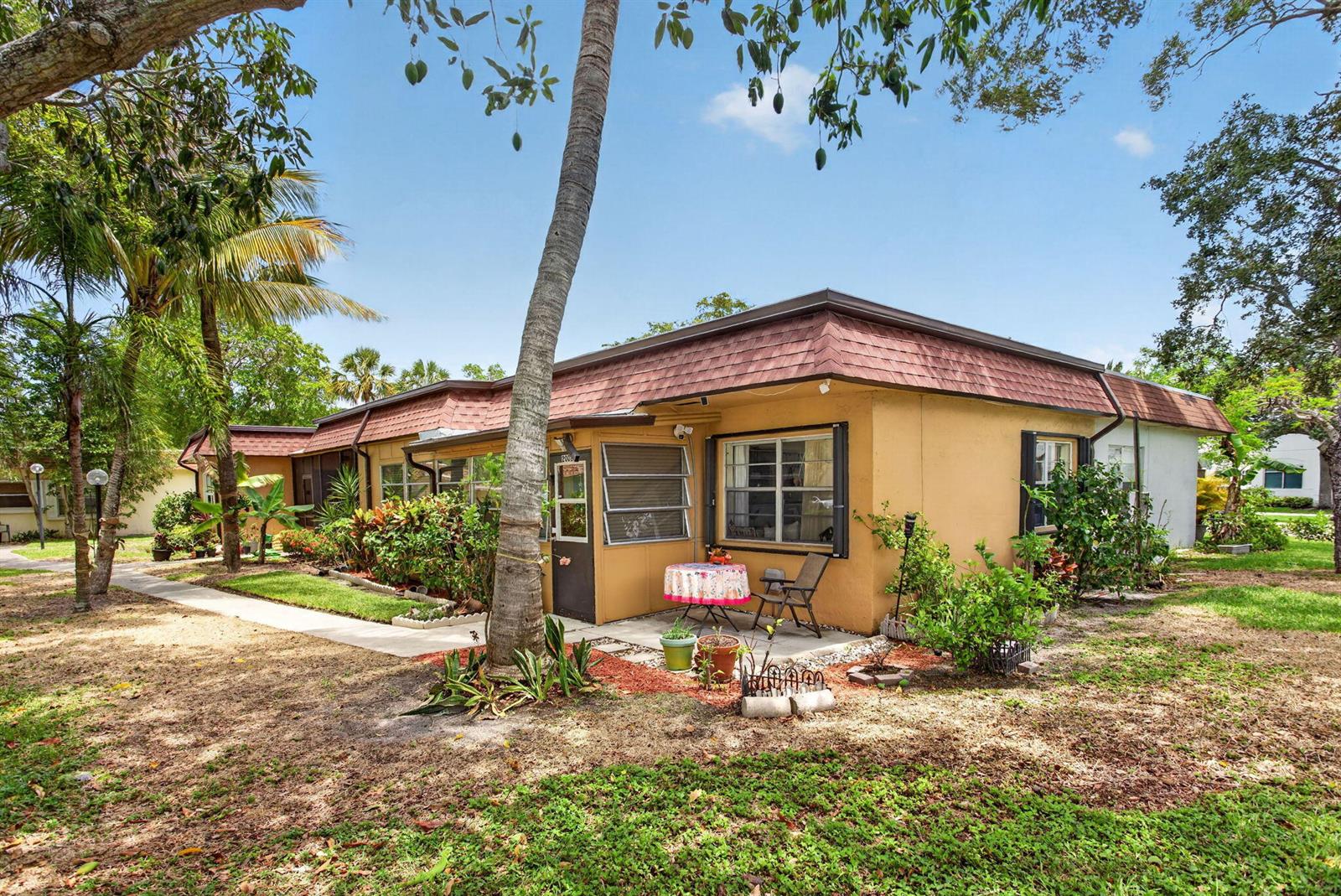 A single-story yellow house with a brown shingled roof and a small patio area — 2002 SW Natura Boulevard # B, Deerfield Beach FL 33441, DEERFIELD BEACH, FL
