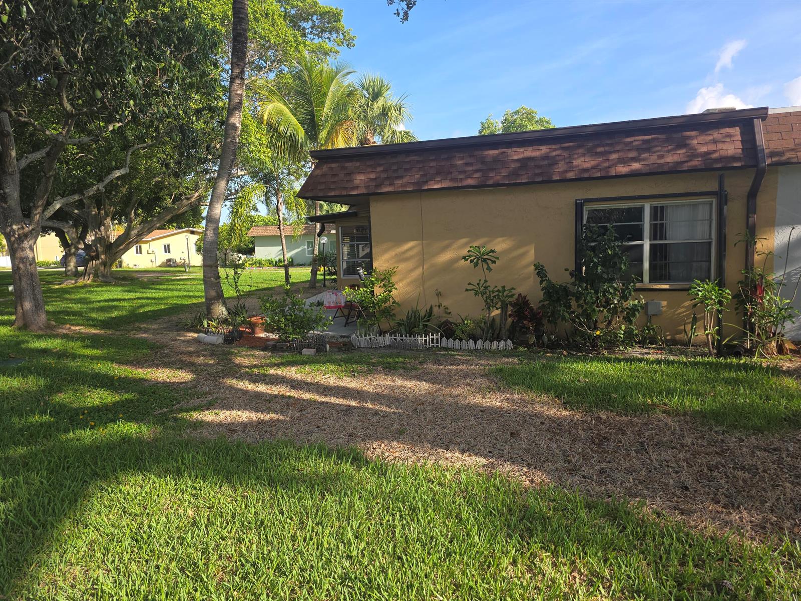 A tan single-story house with a brown shingled roof sits on a grassy lawn — 2002 SW Natura Boulevard # B, Deerfield Beach FL 33441, DEERFIELD BEACH, FL