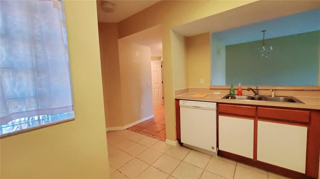A kitchen features white cabinets, a dishwasher, a double sink, and tile flooring — 9612 SEADALE COURT UNIT 101, RIVERVIEW, FL