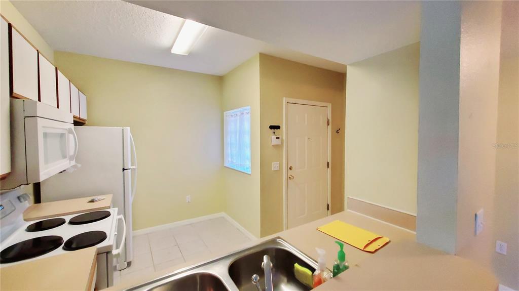 A kitchen features white appliances, light-colored cabinets, a double sink, and a tiled floor — 9612 SEADALE COURT UNIT 101, RIVERVIEW, FL