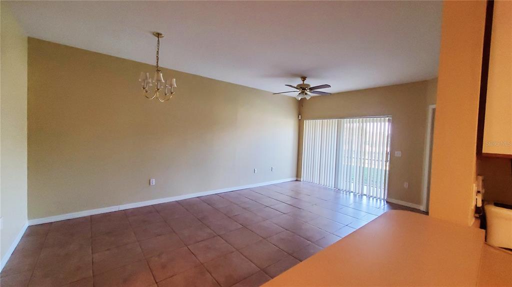 An empty room with tan walls, tile flooring, a ceiling fan, and sliding glass doors — 9612 SEADALE COURT UNIT 101, RIVERVIEW, FL