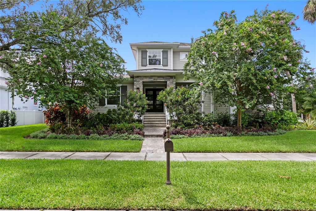 A two-story house with light siding, stone accents, and a landscaped front yard — 5016 W EVELYN DRIVE, TAMPA, FL